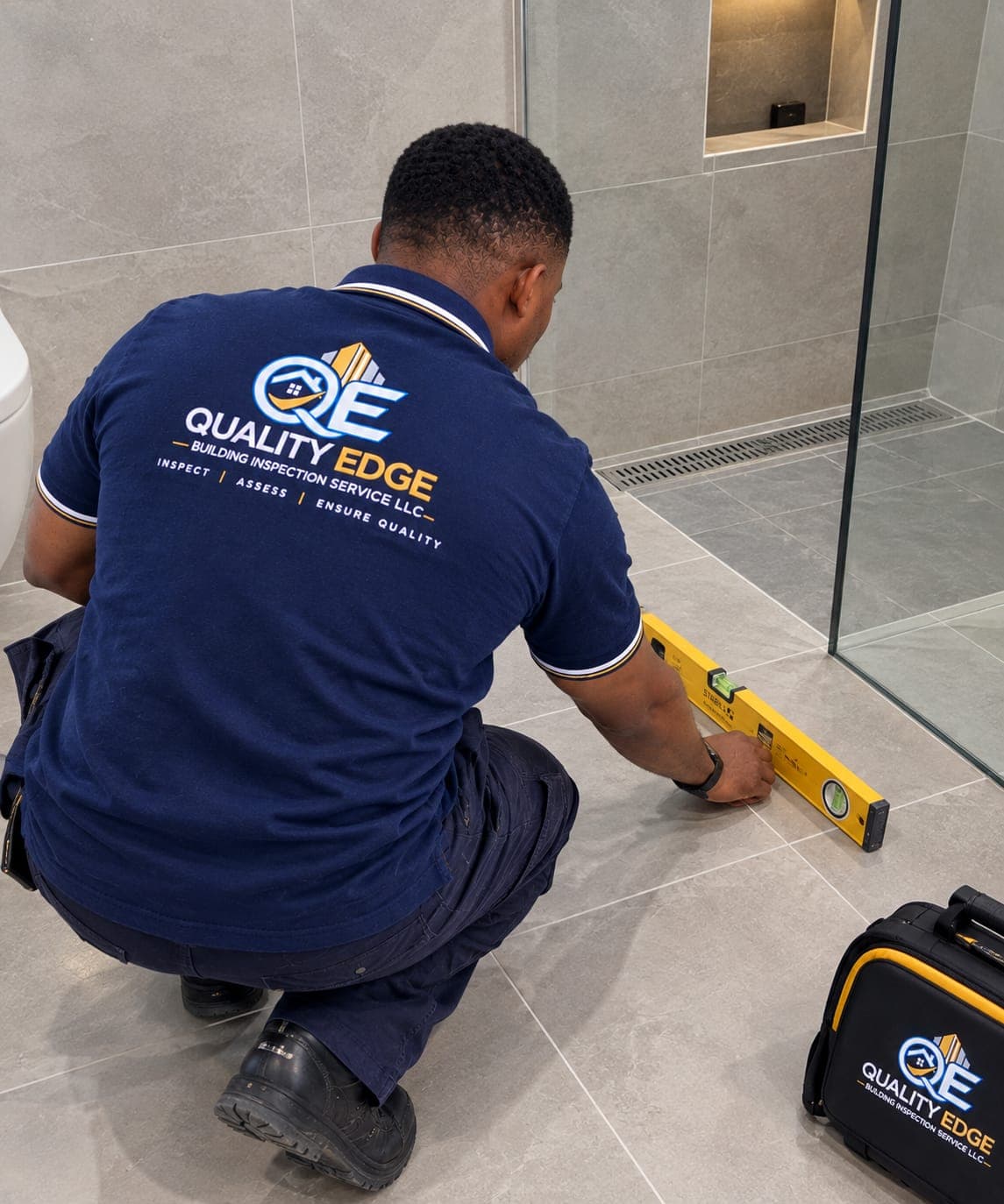 Quality Edge inspector checking floor tile level during a site visit.