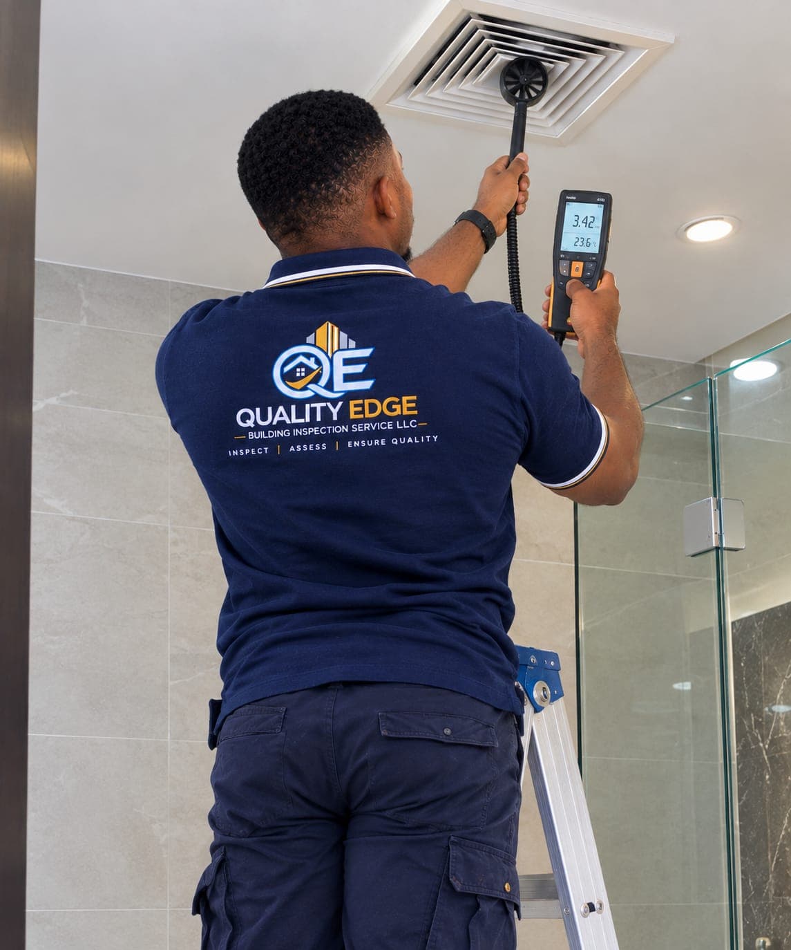 Inspector checking airflow at a ceiling air-conditioning vent.